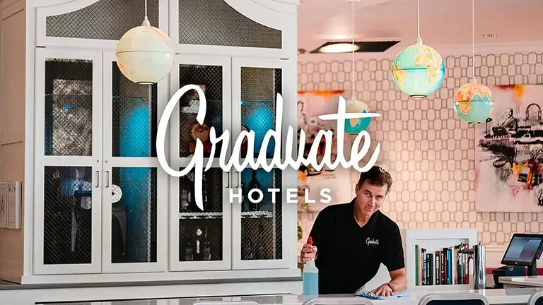 A man standing in front of a window with the words graduate hotels written on it.