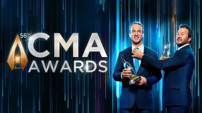 A man holding an award in front of cma awards logo.